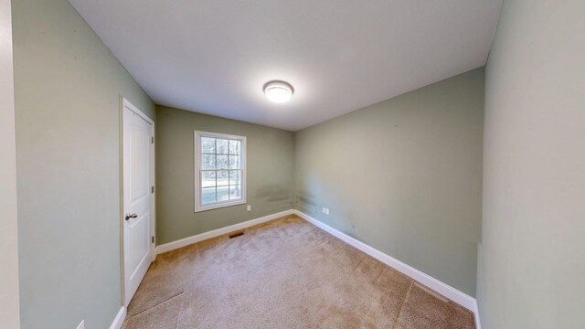 carpeted spare room featuring visible vents and baseboards