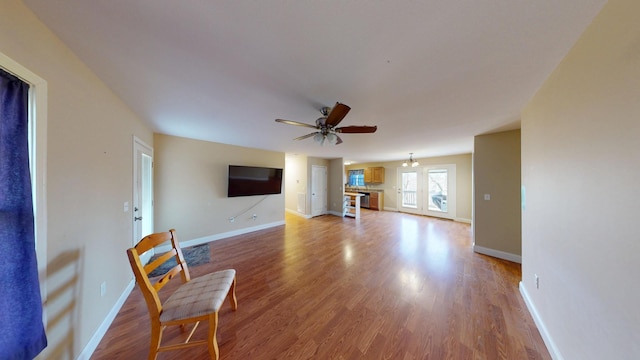 living room featuring light wood-style floors, baseboards, and a ceiling fan