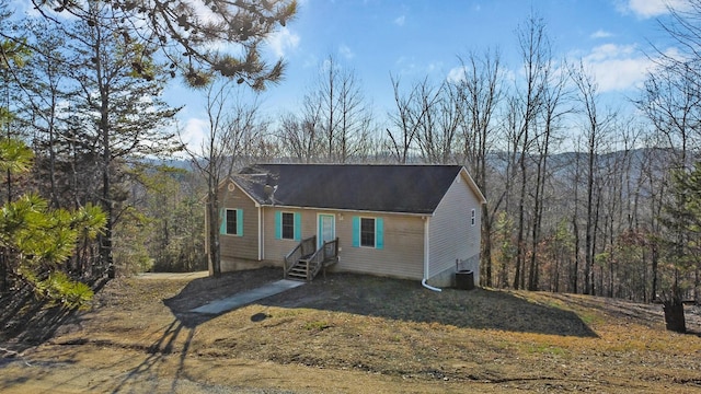 view of front of home with a view of trees and central AC unit