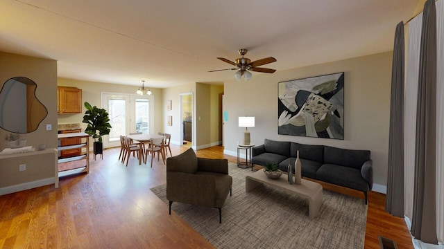 living room featuring light wood-type flooring, baseboards, visible vents, and ceiling fan