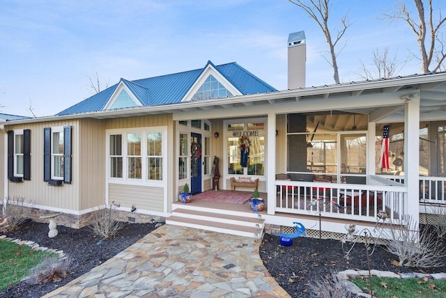 exterior space featuring covered porch, a chimney, and metal roof