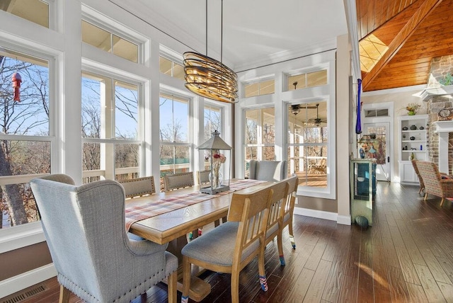 dining area featuring baseboards, visible vents, dark wood finished floors, and crown molding