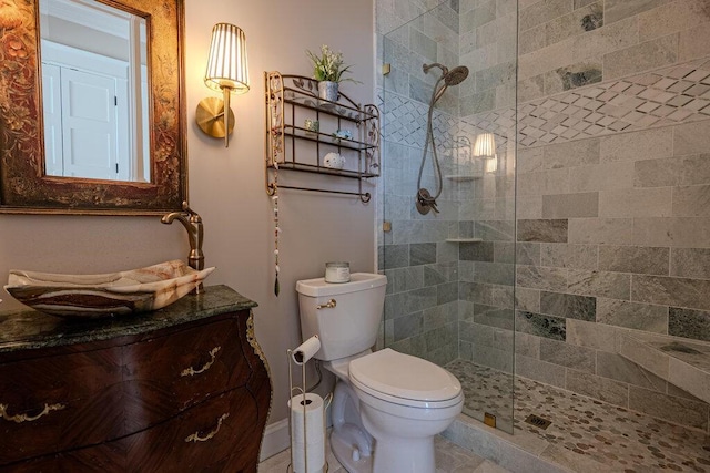 bathroom featuring vanity, a tile shower, and toilet