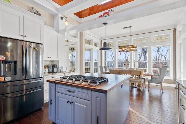 kitchen featuring dark wood-type flooring, butcher block countertops, white cabinetry, ornamental molding, and appliances with stainless steel finishes