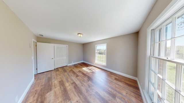 unfurnished bedroom featuring a closet, visible vents, baseboards, and wood finished floors