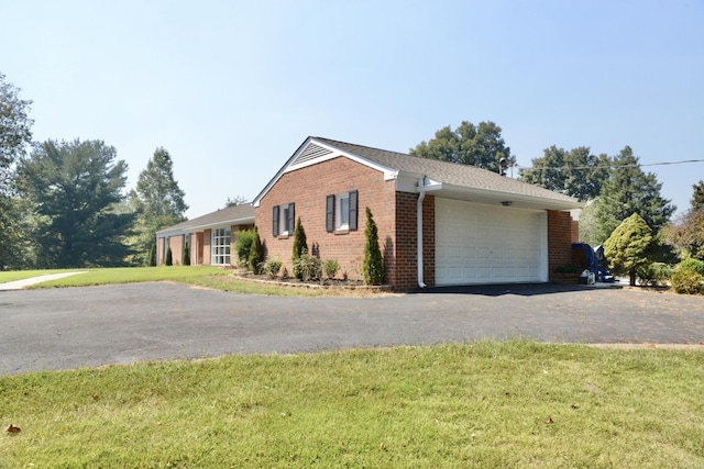 view of front facade featuring aphalt driveway, an attached garage, brick siding, and a front yard