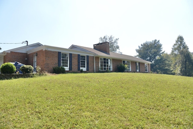 ranch-style house featuring brick siding, a chimney, and a front lawn