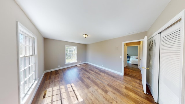 unfurnished bedroom with a closet, wood finished floors, and baseboards