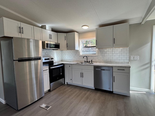 kitchen featuring stainless steel appliances, light countertops, visible vents, a sink, and wood finished floors