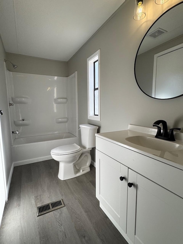 full bath with toilet, vanity, wood finished floors, and visible vents