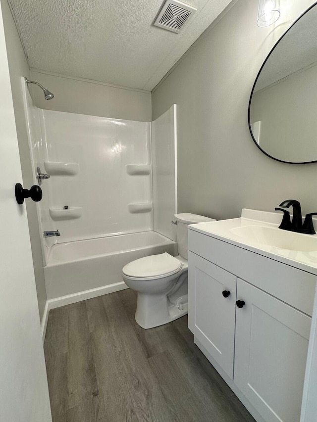 bathroom featuring visible vents, toilet, vanity, a textured ceiling, and wood finished floors