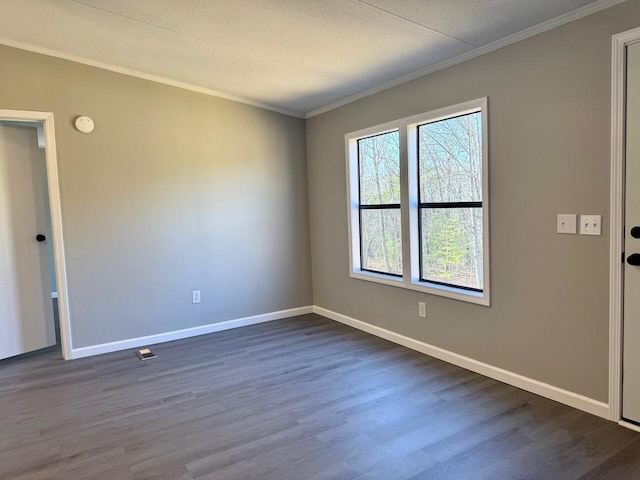 spare room with baseboards, dark wood finished floors, and crown molding