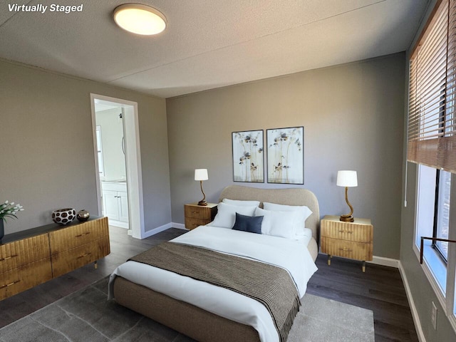 bedroom with ensuite bath, a textured ceiling, baseboards, and wood finished floors