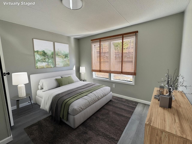 bedroom with a textured ceiling, baseboards, and dark wood-type flooring