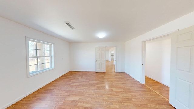 spare room with baseboards, visible vents, and light wood-style floors