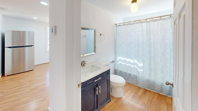 full bath with toilet, shower / bath combo, wood finished floors, and vanity