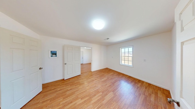 empty room with light wood-type flooring, visible vents, and baseboards