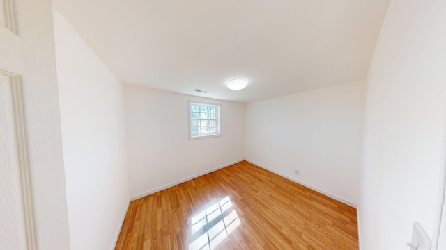 spare room with light wood-style floors, baseboards, and visible vents