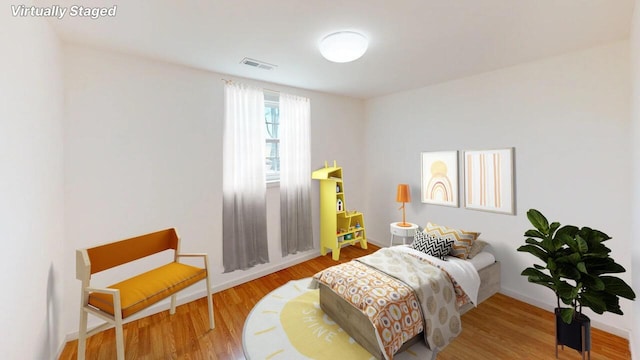 bedroom featuring wood finished floors, visible vents, and baseboards