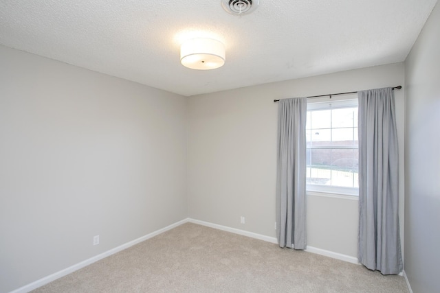 unfurnished room with baseboards, visible vents, a textured ceiling, and light colored carpet