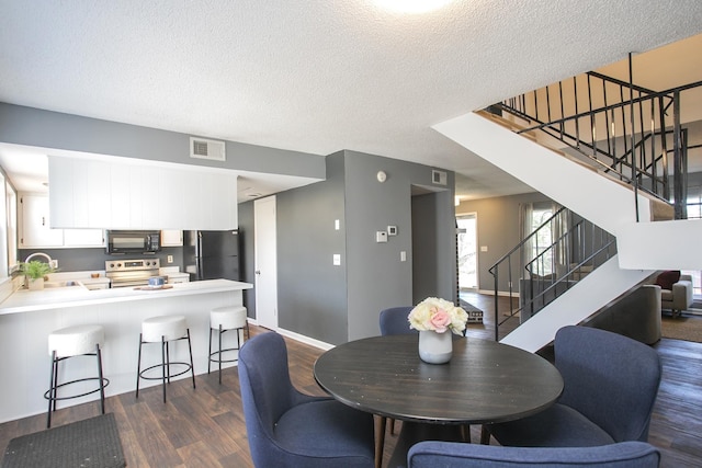 dining room with a textured ceiling, dark wood-style flooring, visible vents, baseboards, and stairs