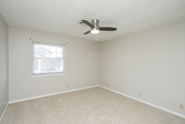 spare room featuring baseboards, a textured ceiling, and light colored carpet