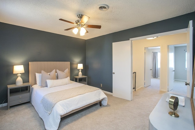 bedroom featuring light carpet, baseboards, visible vents, ceiling fan, and a textured ceiling