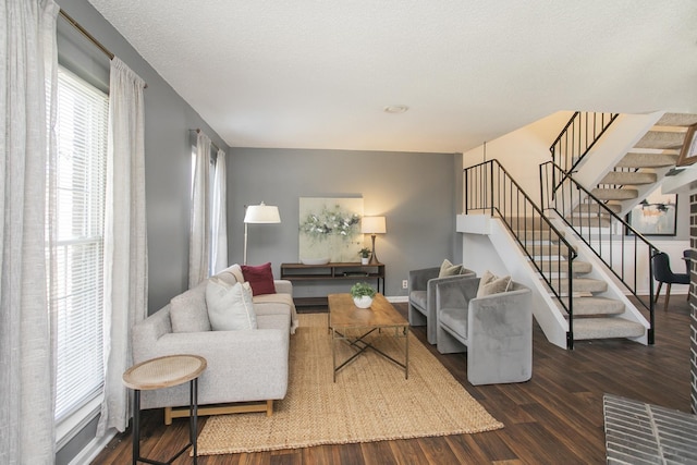 living area with a textured ceiling, stairs, baseboards, and wood finished floors