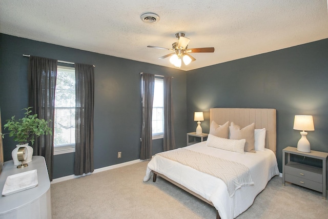 bedroom with baseboards, visible vents, a ceiling fan, light colored carpet, and a textured ceiling