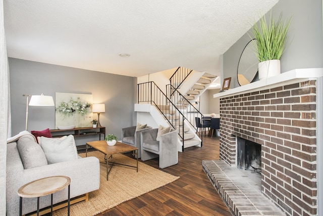 living area with a fireplace, stairway, a textured ceiling, and wood finished floors