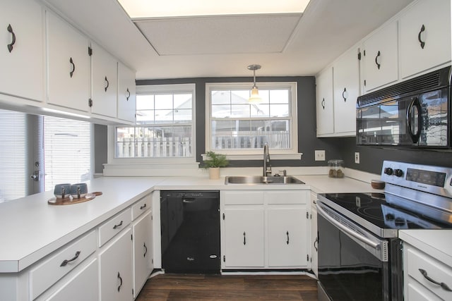 kitchen with white cabinets, a peninsula, light countertops, black appliances, and a sink