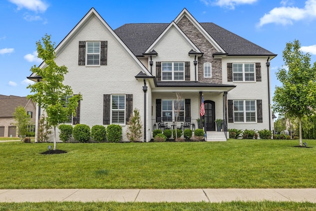 view of front of house with a front lawn, a porch, and brick siding