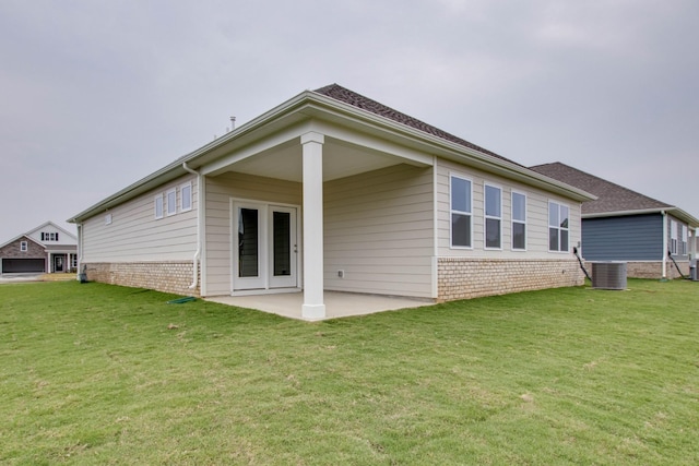 back of property featuring brick siding, a lawn, central AC unit, and a patio