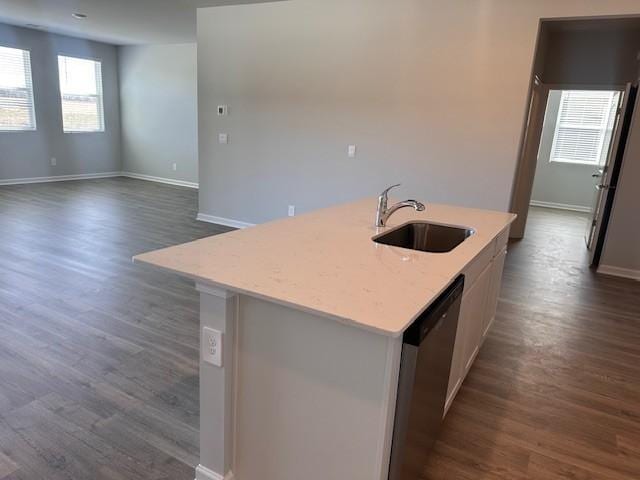 kitchen featuring dishwashing machine, a sink, baseboards, dark wood finished floors, and a center island with sink