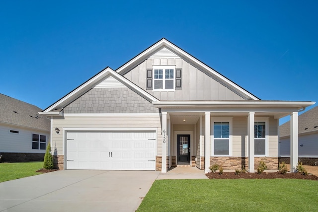 craftsman-style home featuring driveway, stone siding, board and batten siding, and a front yard