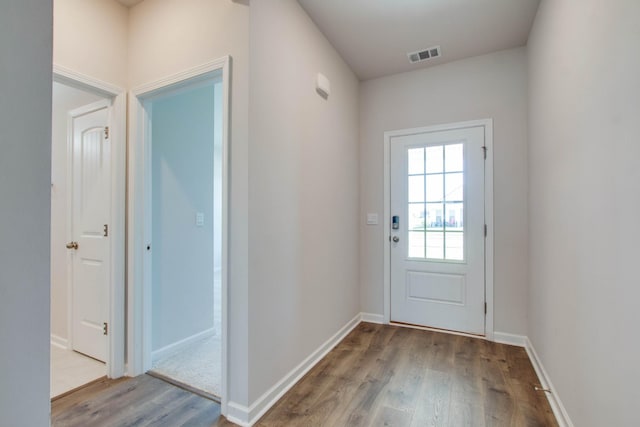 doorway to outside featuring baseboards, visible vents, and wood finished floors