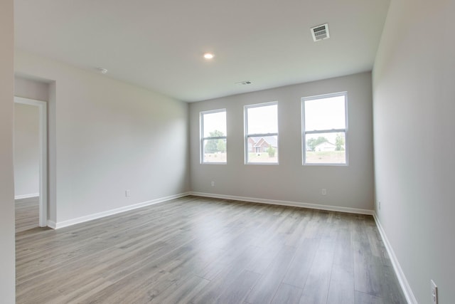 empty room with wood finished floors, visible vents, and baseboards