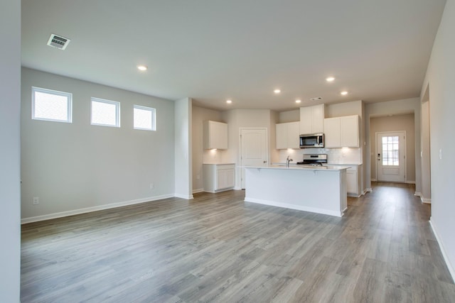 kitchen featuring visible vents, light wood-style flooring, appliances with stainless steel finishes, open floor plan, and white cabinets