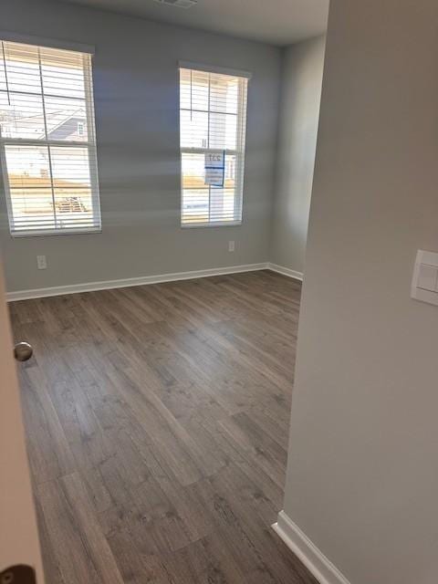 unfurnished room featuring visible vents, dark wood finished floors, and baseboards