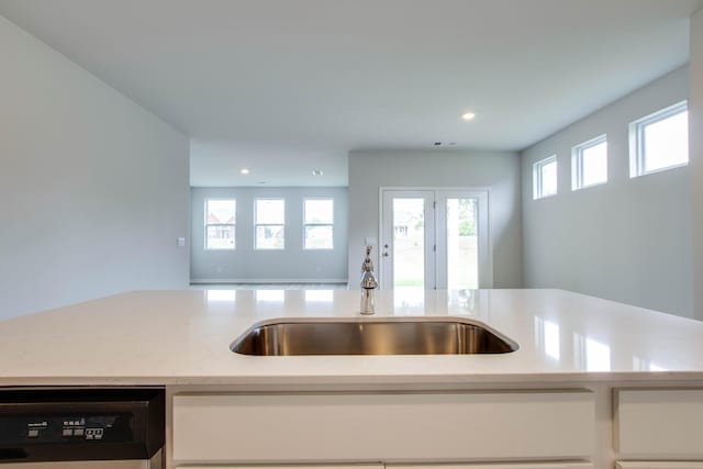 kitchen featuring recessed lighting, open floor plan, white cabinets, a sink, and dishwasher