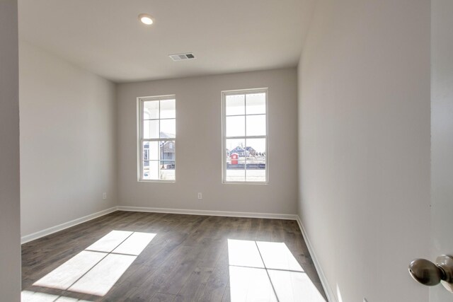 spare room with baseboards, visible vents, and dark wood-type flooring