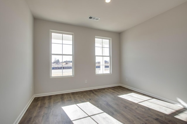 spare room with visible vents, dark wood-type flooring, and a wealth of natural light