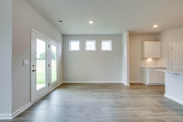 unfurnished living room featuring light wood-style floors, baseboards, visible vents, and recessed lighting