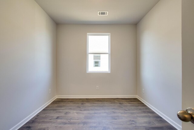 empty room featuring baseboards, visible vents, and dark wood-style flooring