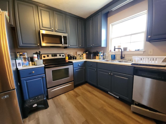 kitchen featuring light wood finished floors, stainless steel appliances, a sink, and light countertops