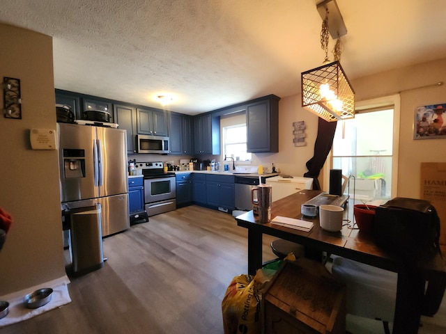 kitchen with dark wood-type flooring, a sink, light countertops, appliances with stainless steel finishes, and blue cabinetry