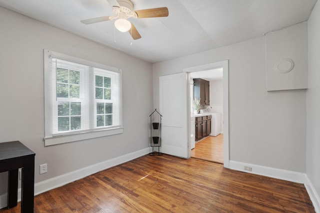 empty room with a ceiling fan, baseboards, and wood finished floors