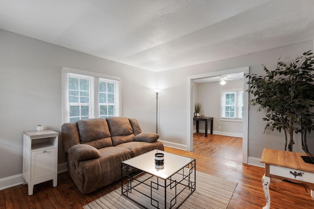 living room featuring a textured ceiling, baseboards, and wood finished floors