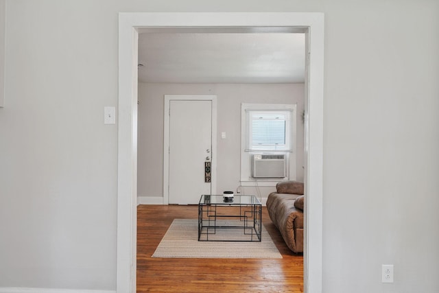 corridor featuring wood finished floors, cooling unit, and baseboards