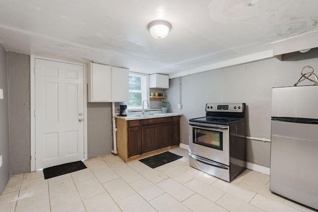 kitchen featuring baseboards, white cabinets, appliances with stainless steel finishes, light countertops, and a sink